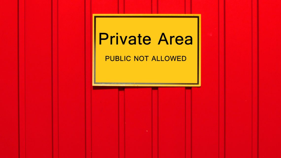 Auf dem Bild sieht man ein gelbes Schild auf einem roten Zaun. Auf dem Schild steht: "Private Area. Public is not allowed"